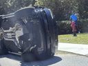 Golfer Tiger Woods stands by his overturned vehicle in Jupiter Island, Fla..