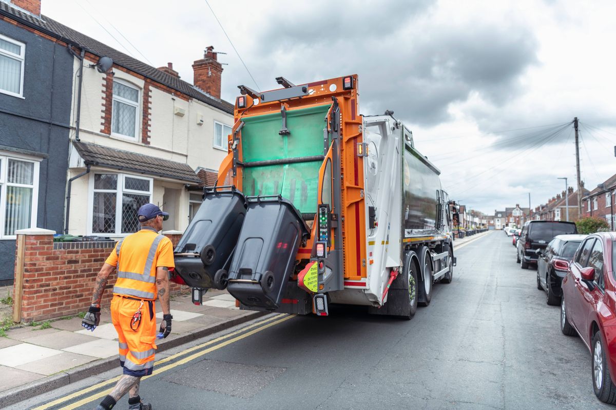 Refuse collector and refuse truck in street