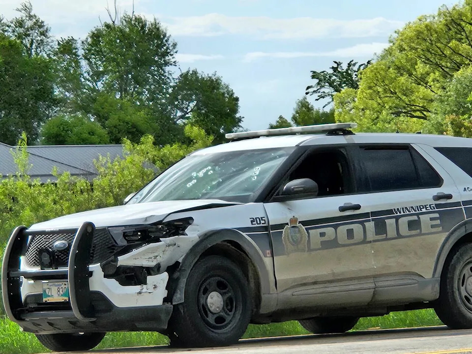 A Winnipeg police cruiser with bullet holes in the windshield is parked at the side of the highway south of Niverville.