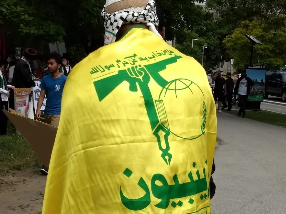 A man wears a Hezbollah flag as a cape during an al-Quds day rally at Queen’s Park in Toronto on June 9, 2018.