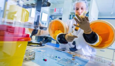 A photo of a female healthcare worker preparing chemotherapy treatments under a glove box.