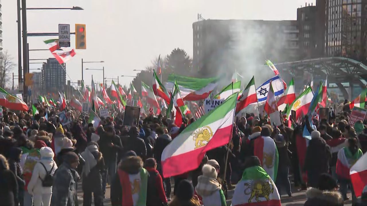 People in crowd on road holding variety of flags 