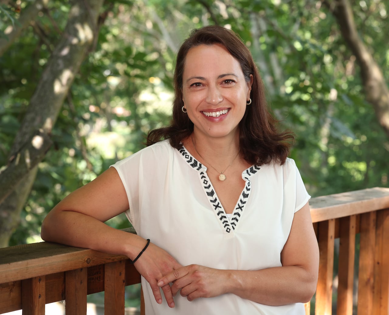 A woman with a white shirt smiles at the camera.