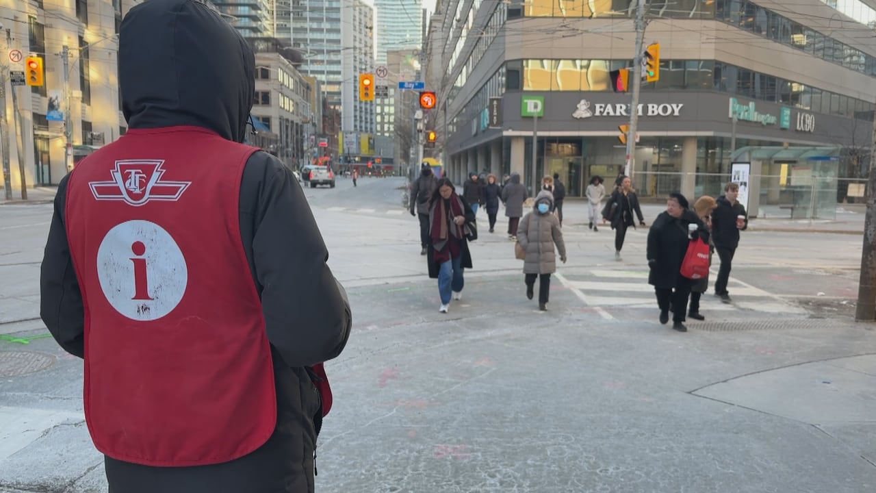 Transit information person at corner of sidewalk as people cross