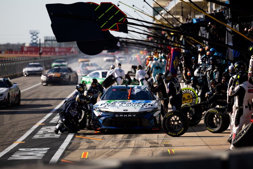 A NASCAR pit crew works on a car at a race. 