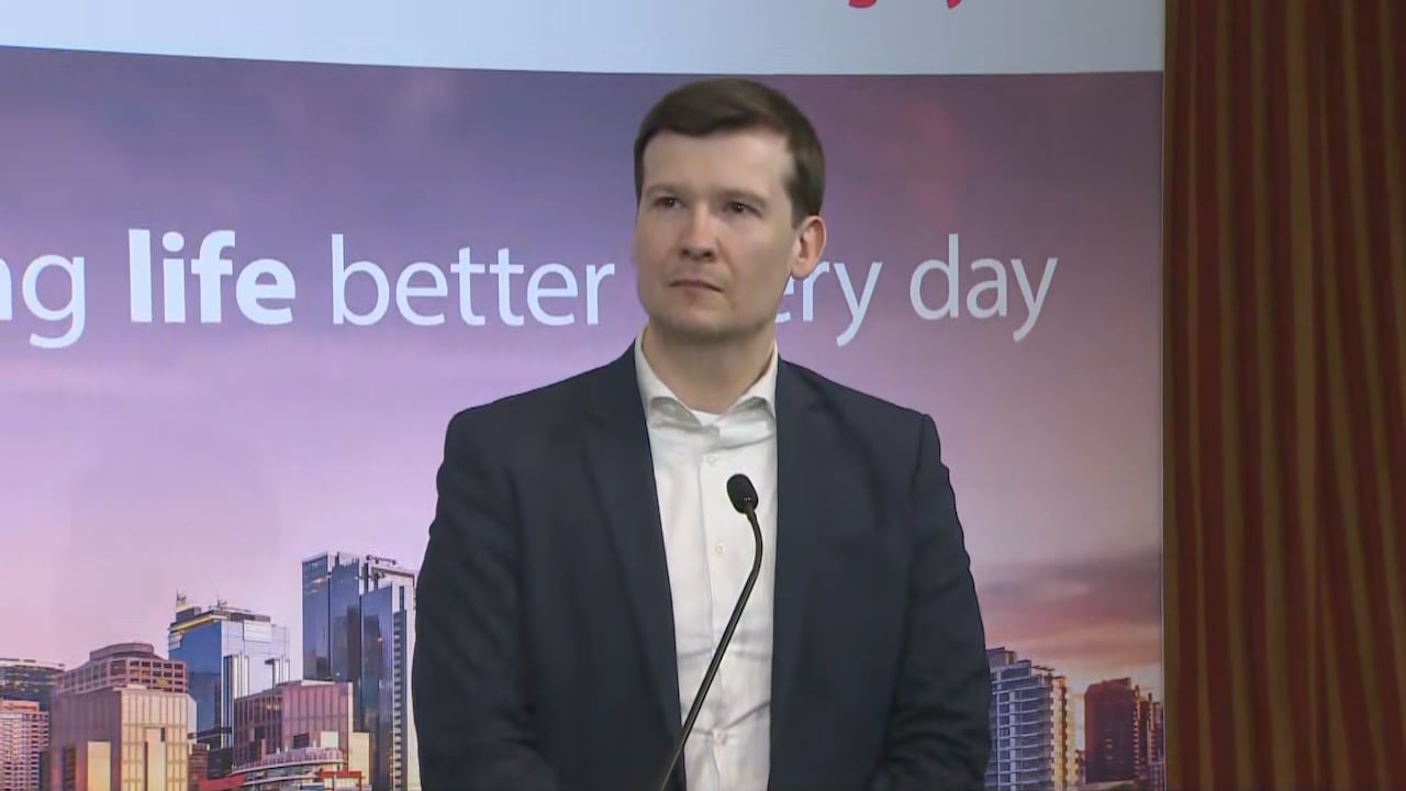Calgary's mayor stands at a podium, looking at someone past the camera.