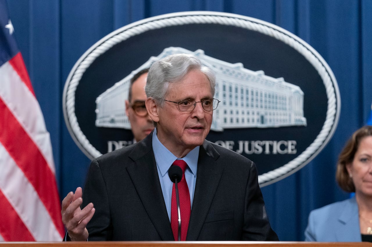 a man with white hair and glasses stands behind a podium speaking