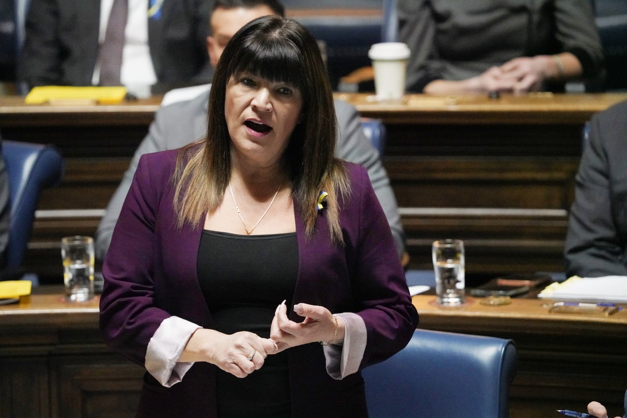 A woman in a purple blazer speaks during a government legislative session.