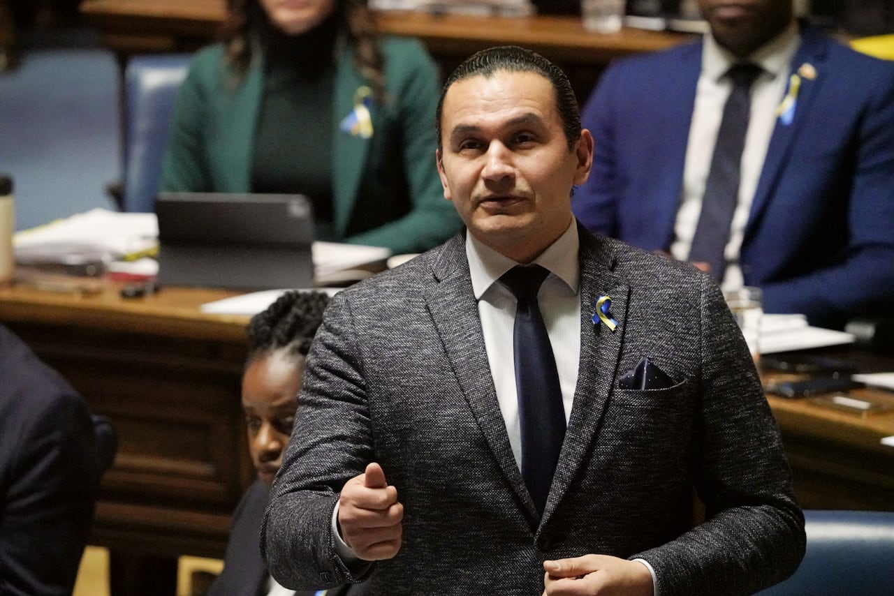 A man in a dark grey-ish suit speaks during a government legislative session.