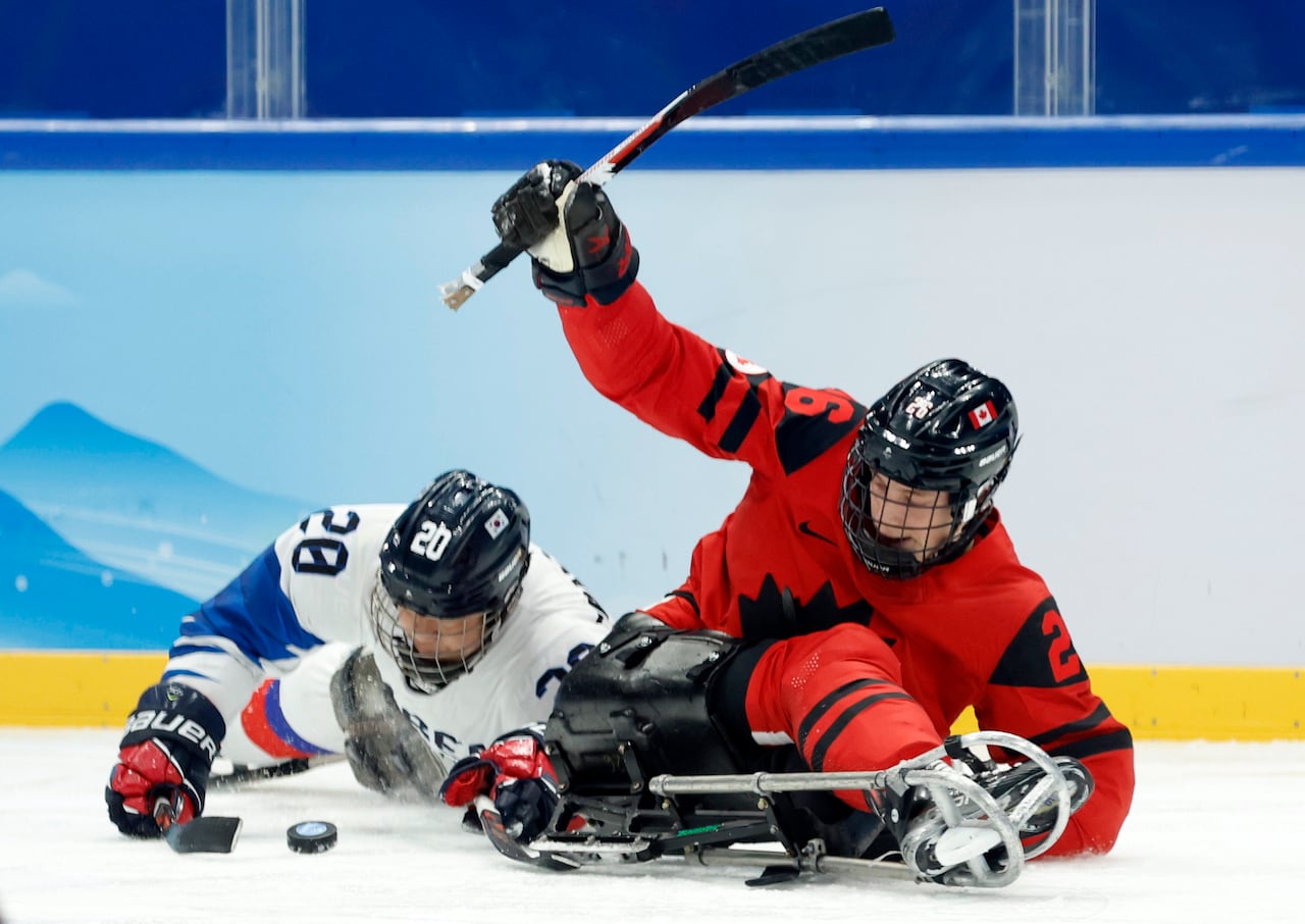Two para hockey players jostle for a puck.