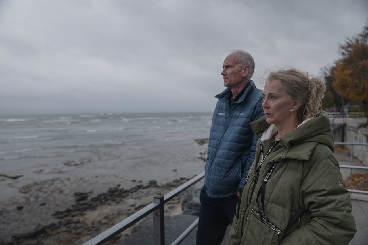 A middle-aged couple look out over a large body of water 