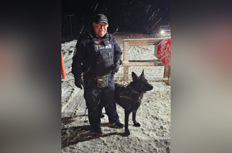 A man stands with a dog in an open field.