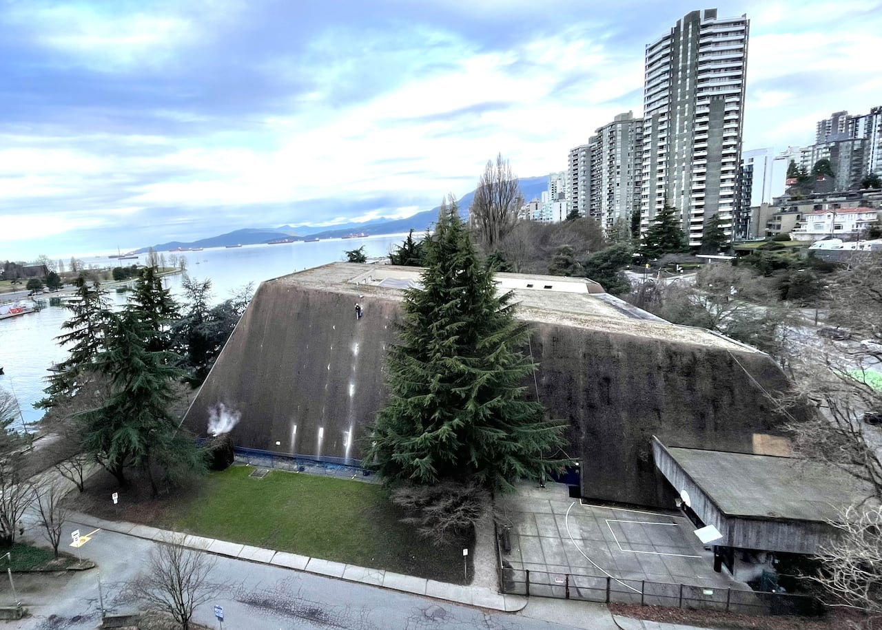 A worker rappels down the side of the Vancouver Aquatic Centre.
