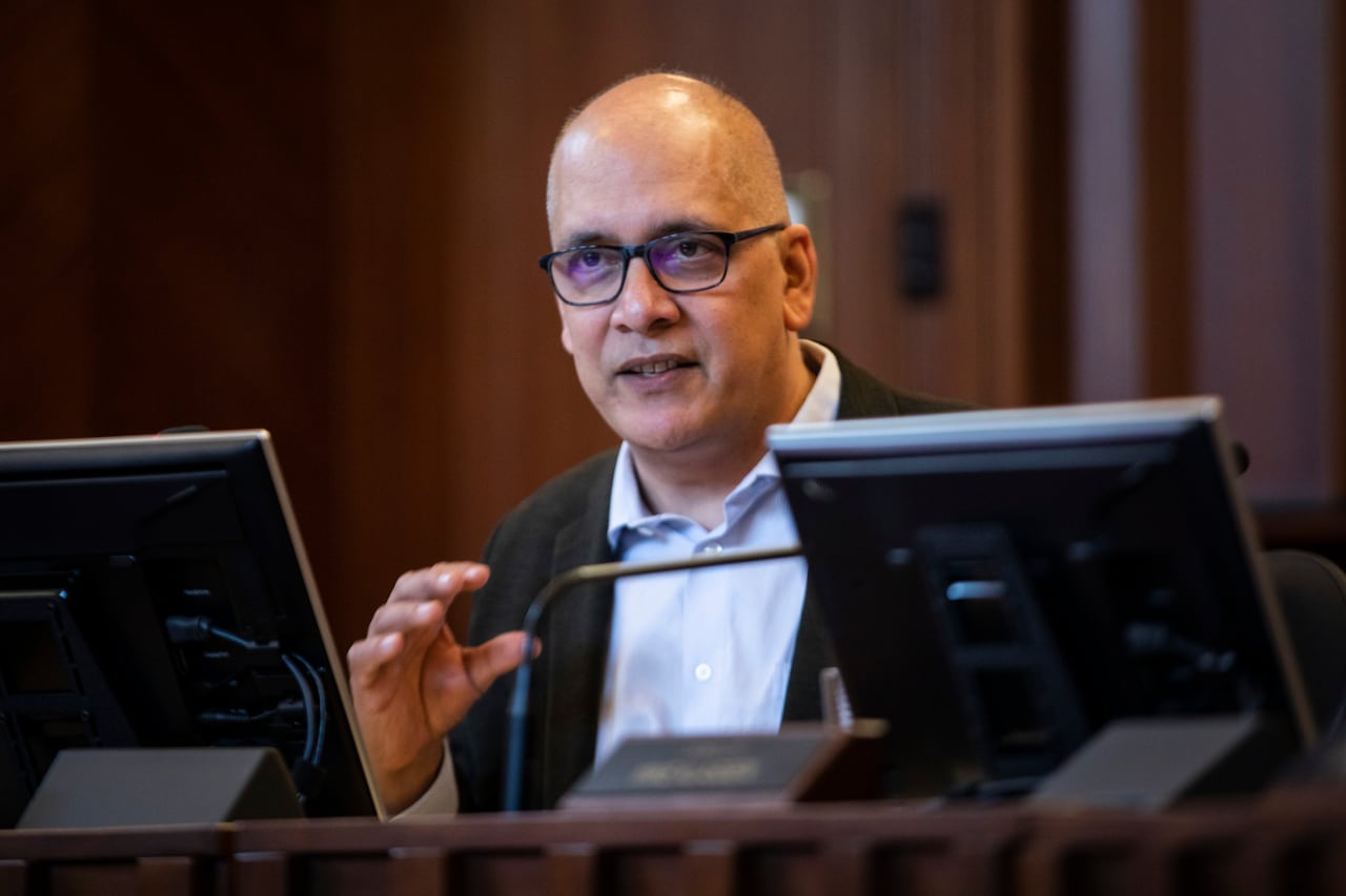 A bald man wearing glasses speaks in council chambers.