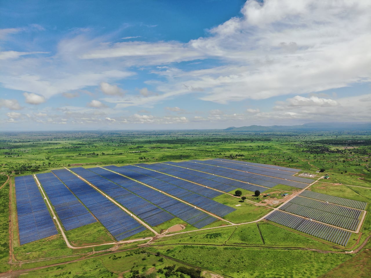 Aerial view of a huge field of solar panels surrounded by green grass