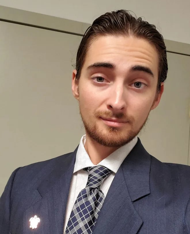 A man wearing a suit smiles at the camera