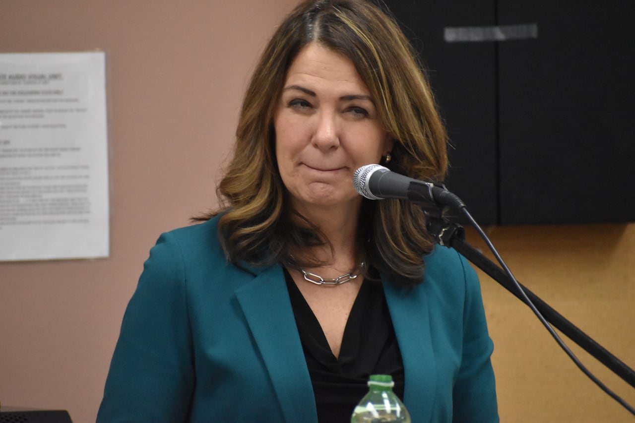 Premier Danielle Smith stands at a microphone