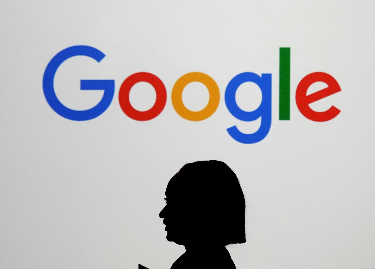 A woman walks by a giant screen with a Google logo at an event at the Paris Google Lab