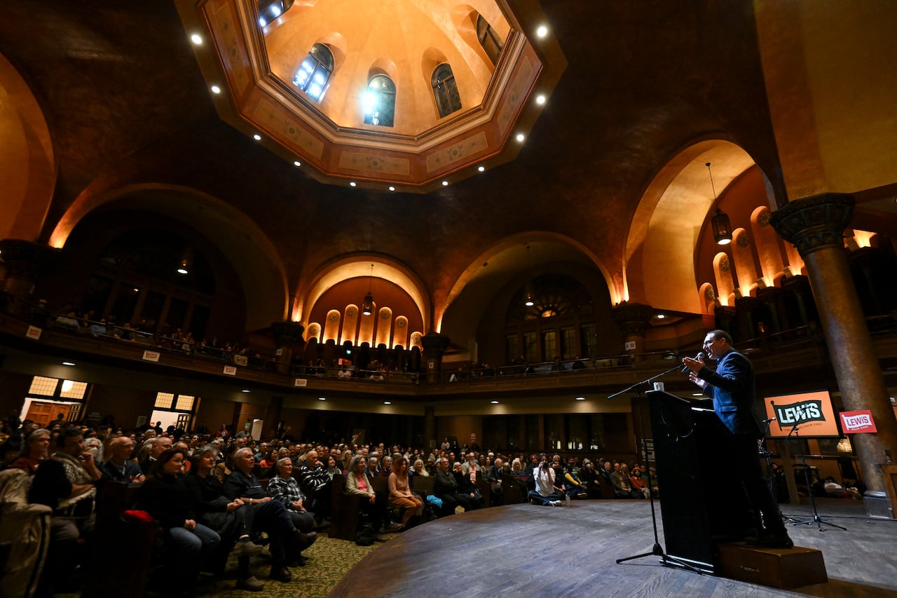 A wide shot of the venue shows the audience of about 500 people listening to Avi Lewis speak on stage.