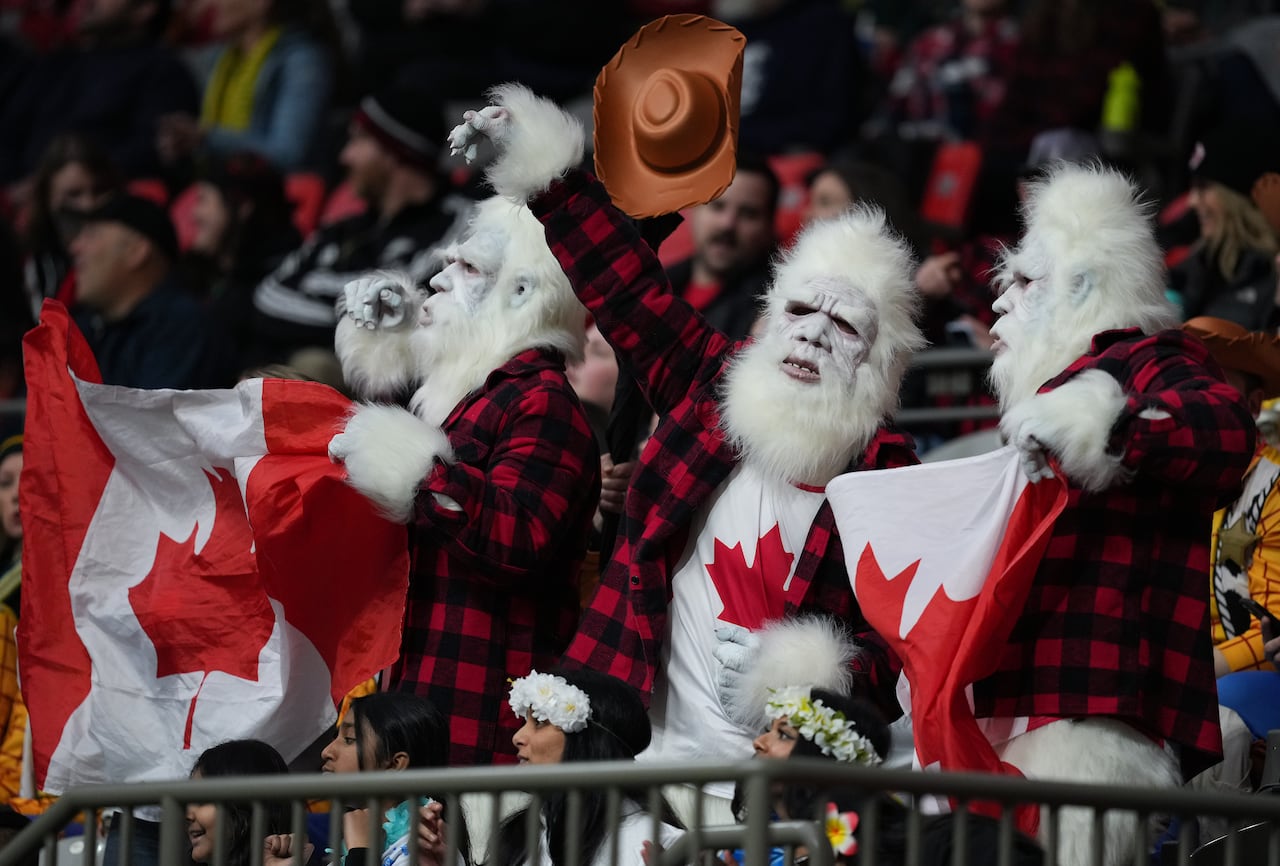 Fans dressed up as yetis hold Canadian flags.
