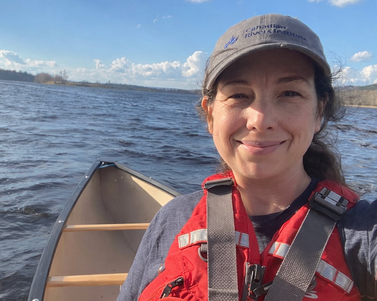 A woman with a lifejacket and cap in a boat