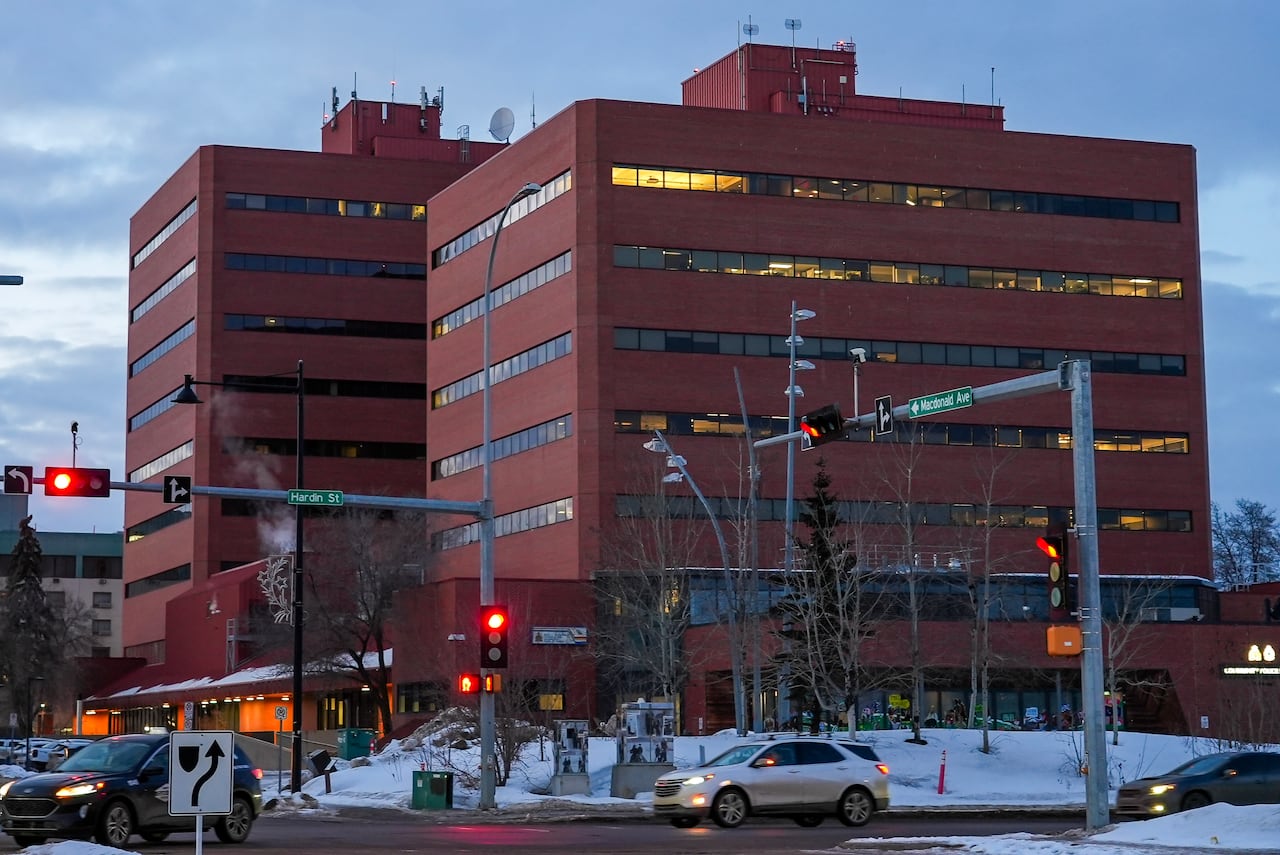 Vehicles drive past a large red building.
