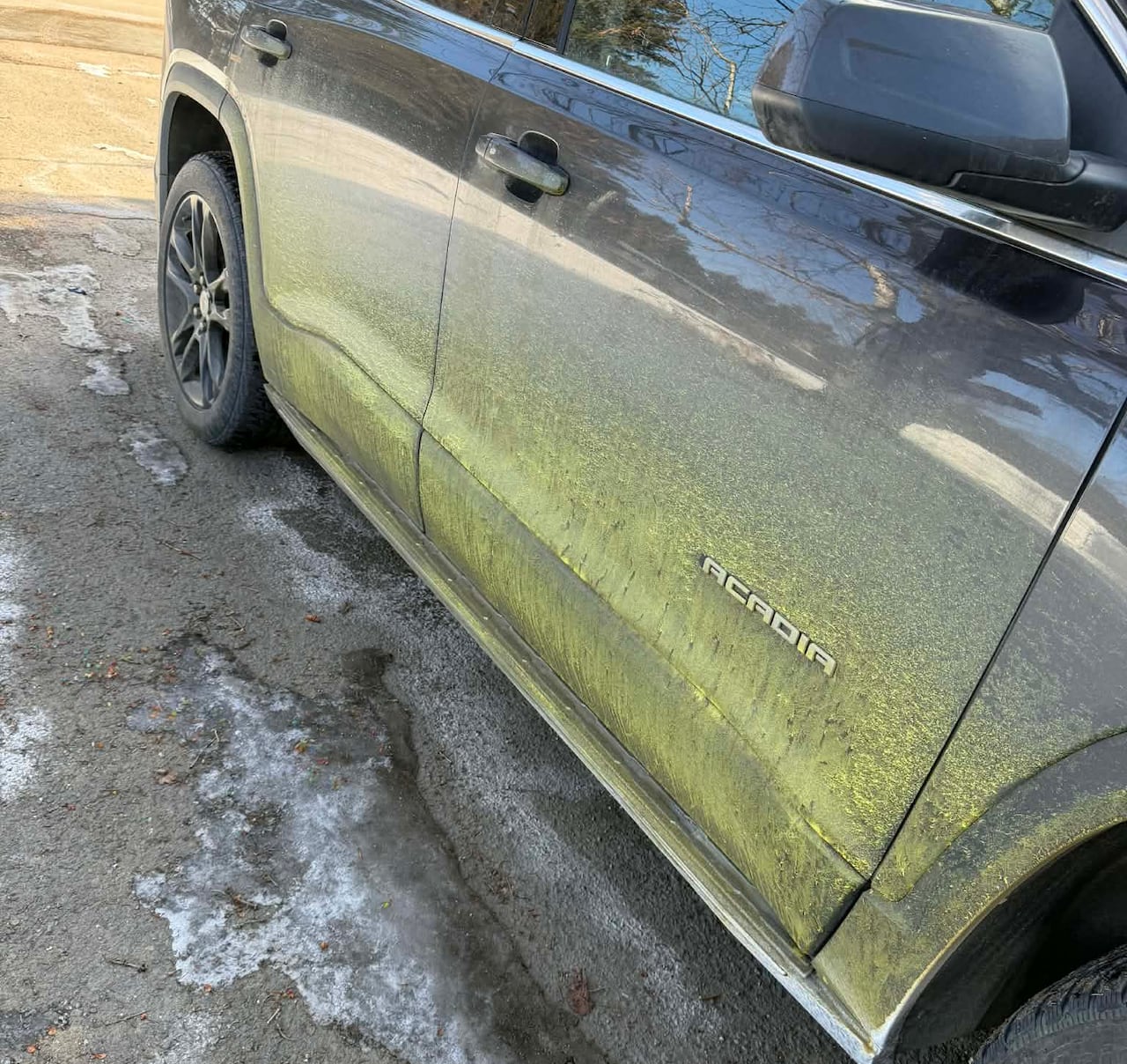 A car with stains of yellow on the bottom half of the doors.