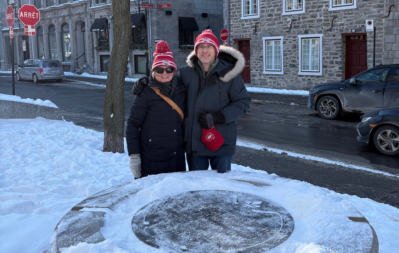 Two people stand in the snow behind a commemorative plaque where Montreal's first well was dug in 1658.