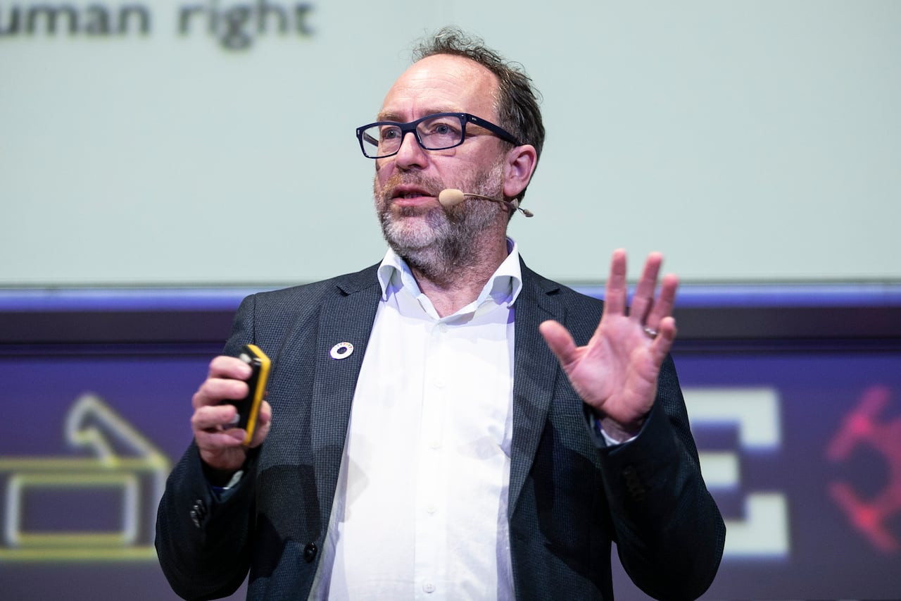 A man is speaking into a microphone while wearing a suit.
