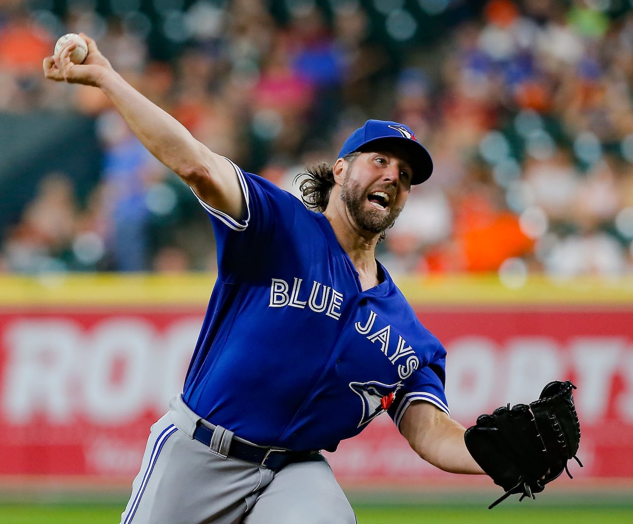 A baseball pitcher in the middle of his wind-up, while throwing to the catcher during an MLB game
