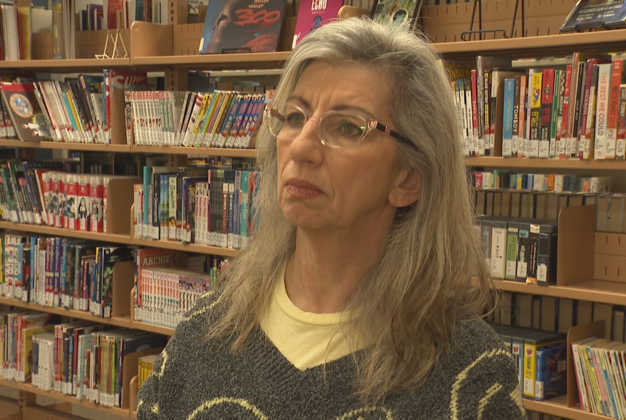 Woman, with books behind her, looking at camera.