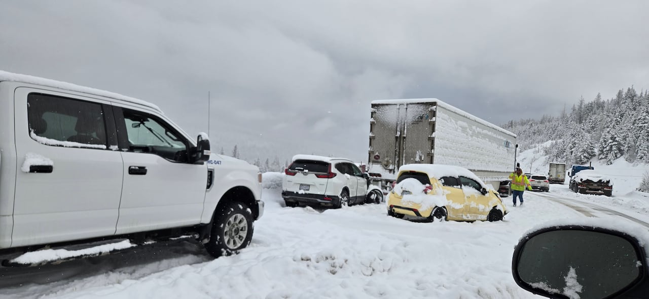 Several vehicles sit in deep snow along a highway.