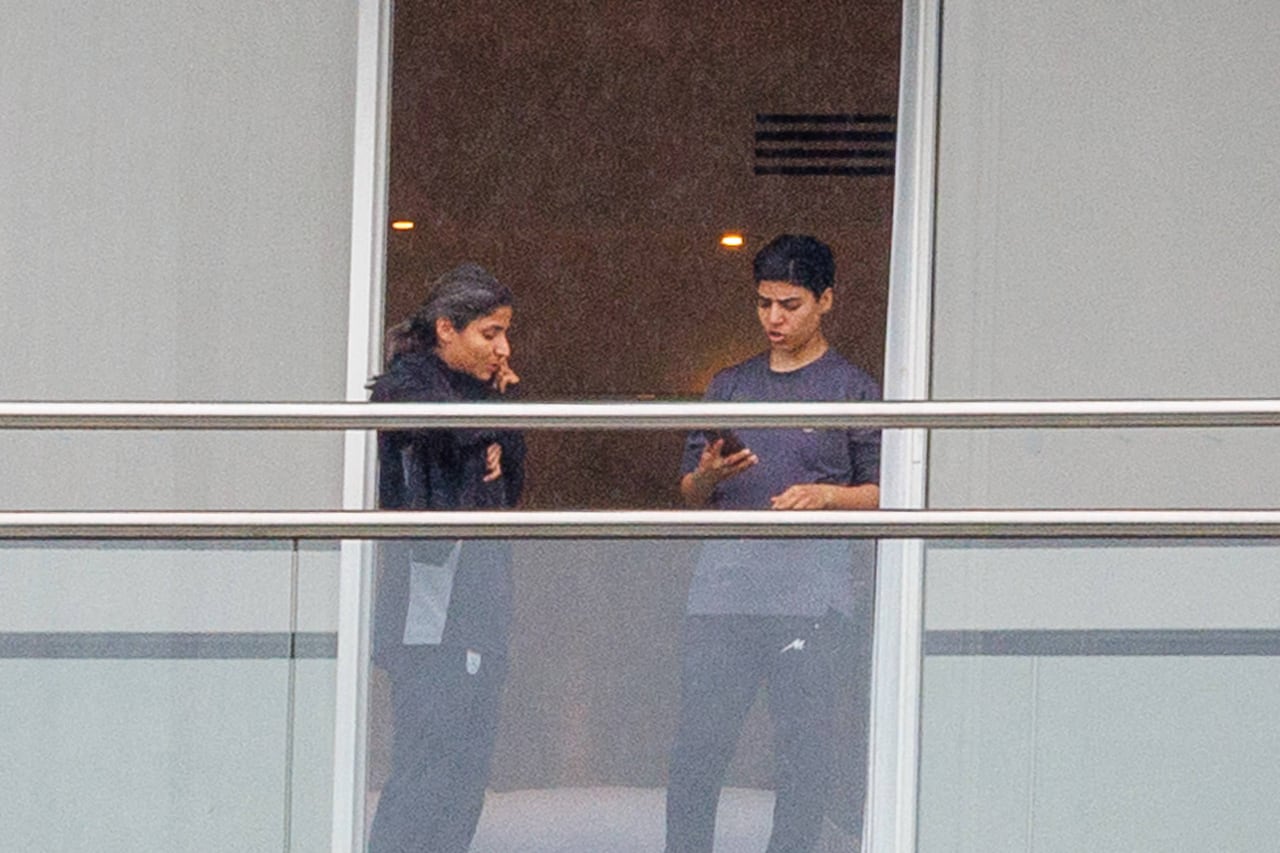 Two women stand on a balcony.