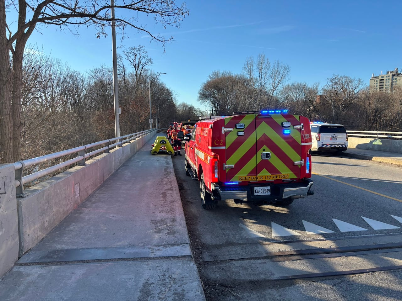 London Fire Department rescue vehicles and emergency crews stopped on a bridge near the Thames River during a rescue response.