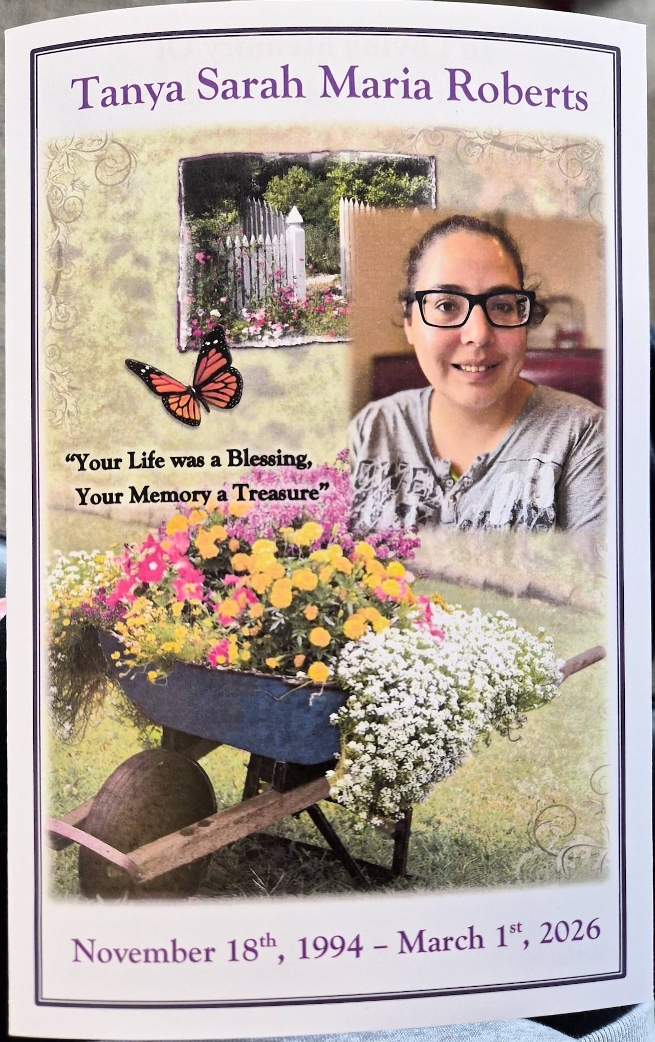 An obituary picture shows a wagon filled with flowers next to a picture of a woman with brown hair wearing black glasses and a grey shirt. 