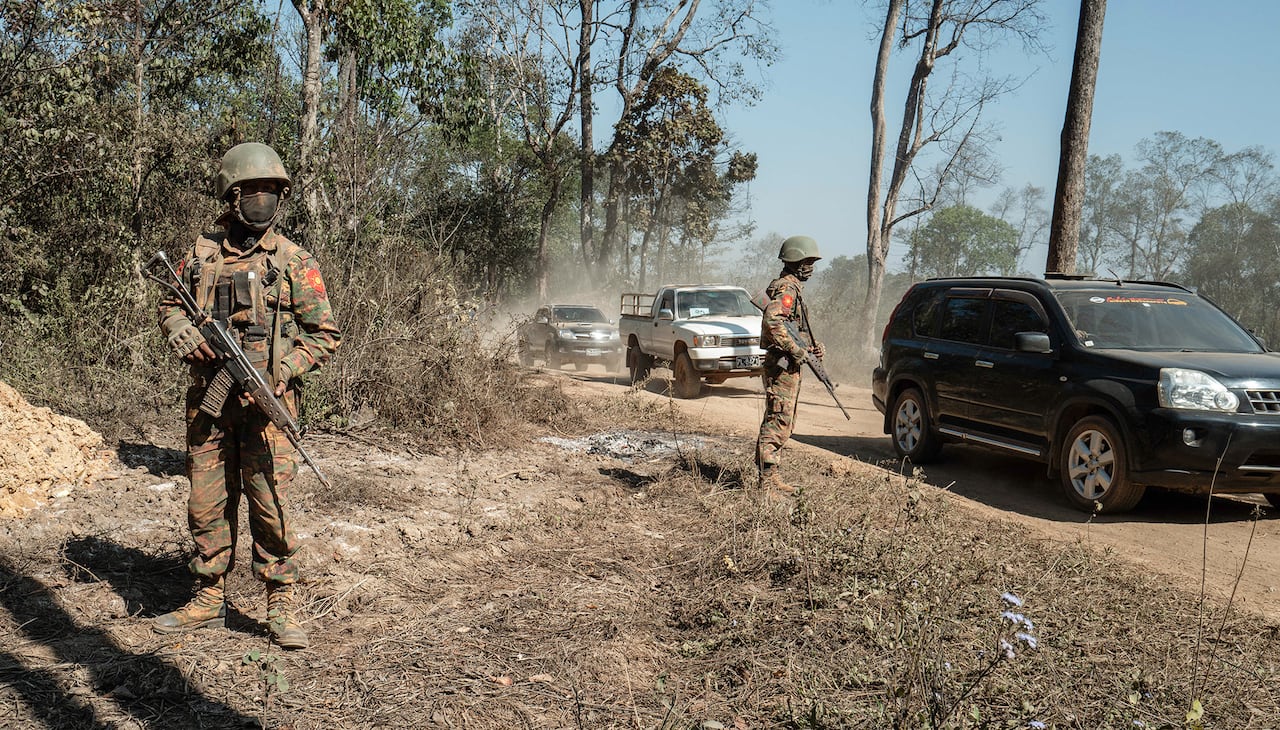 Soldiers are seen walking outside, with trucks nearby.