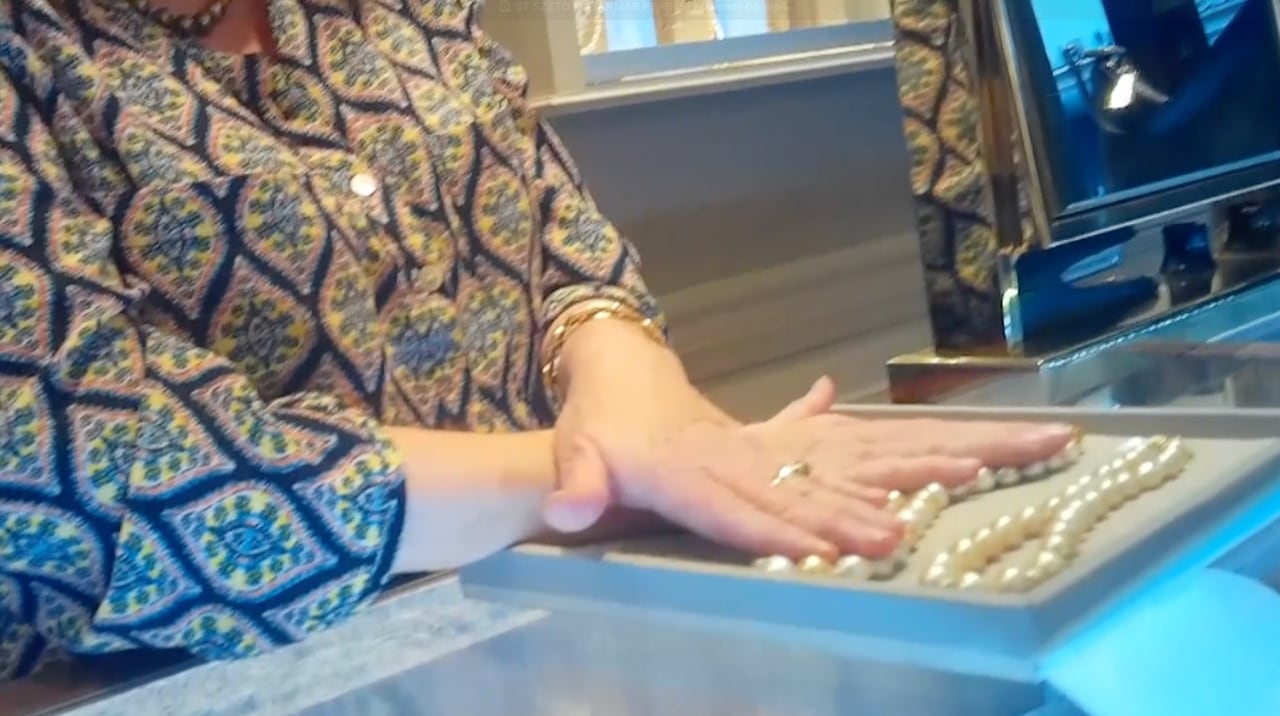 A person touches a display of pearls.