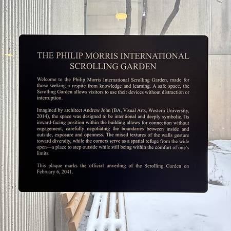Photo of a historical plaque pasted on a window. It is labelled The Philip Morris International Scrolling Garden