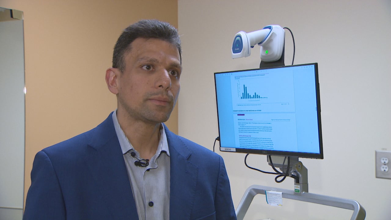 A man stands in front of a computer monitor.