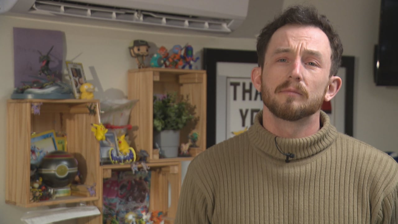 A man wearing a turtleneck is seen in a collectibles store.