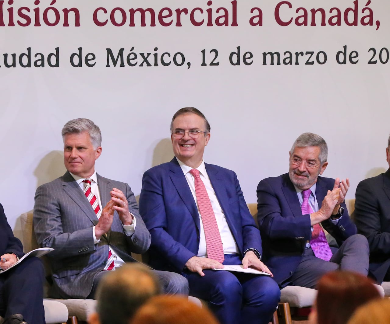 Three men in suits sitting next to each other.