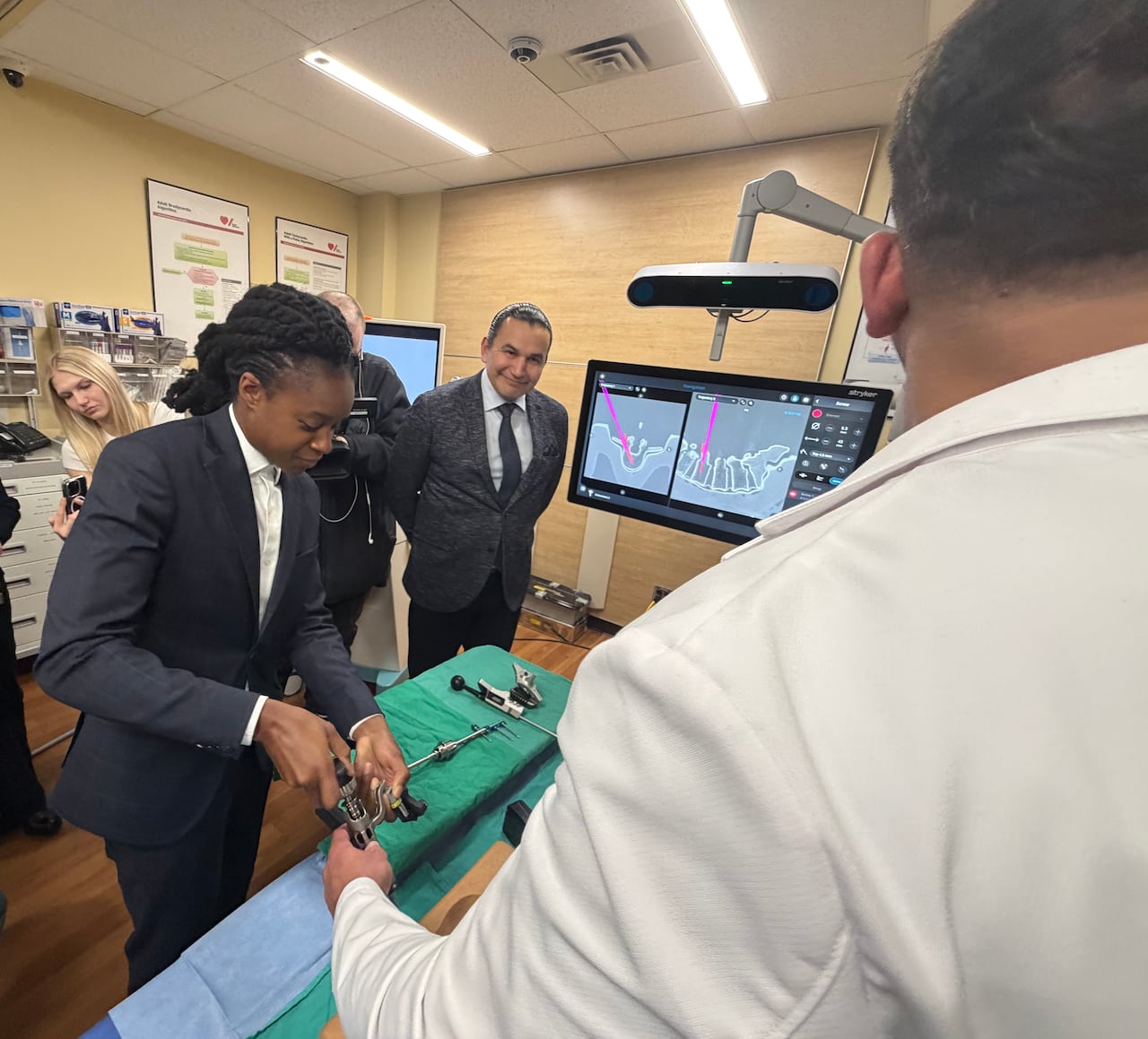 A doctor shows a politician how to use surgical tools.