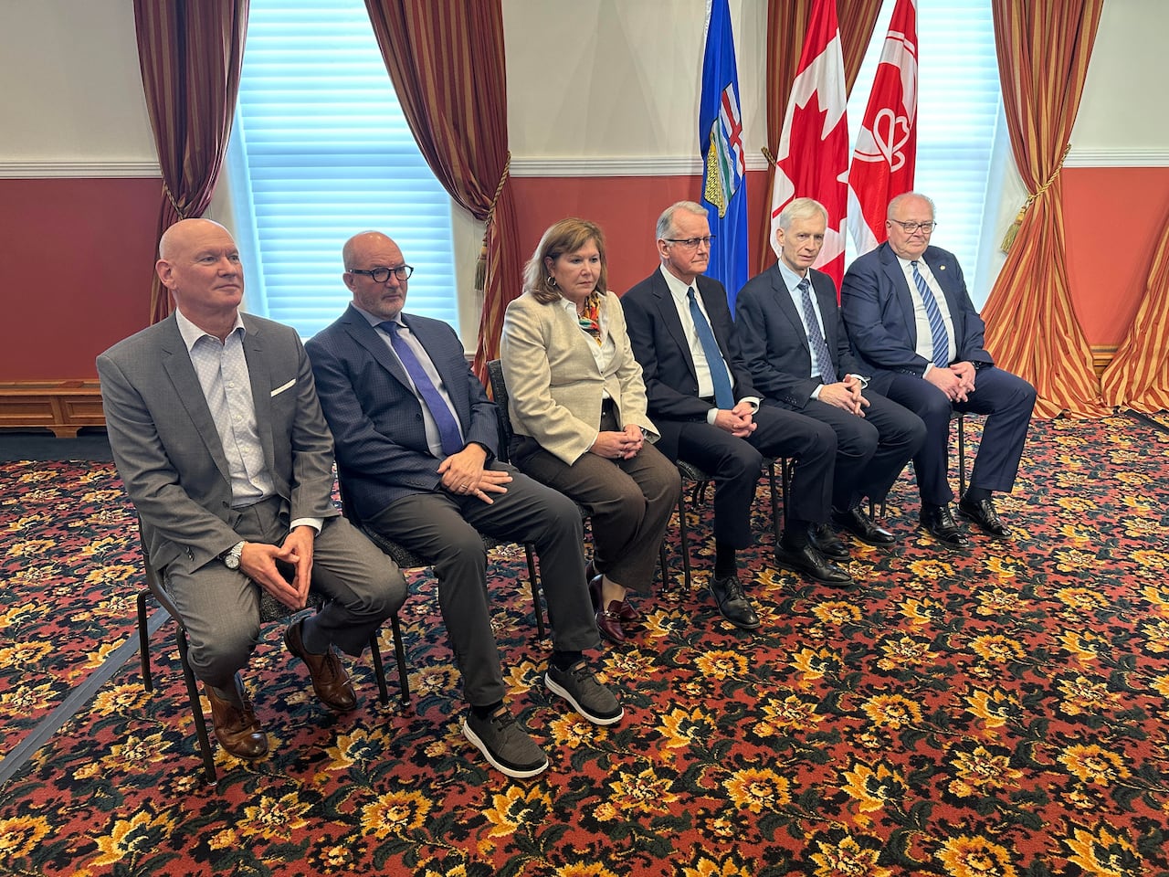 Six people sitting on chairs in a line