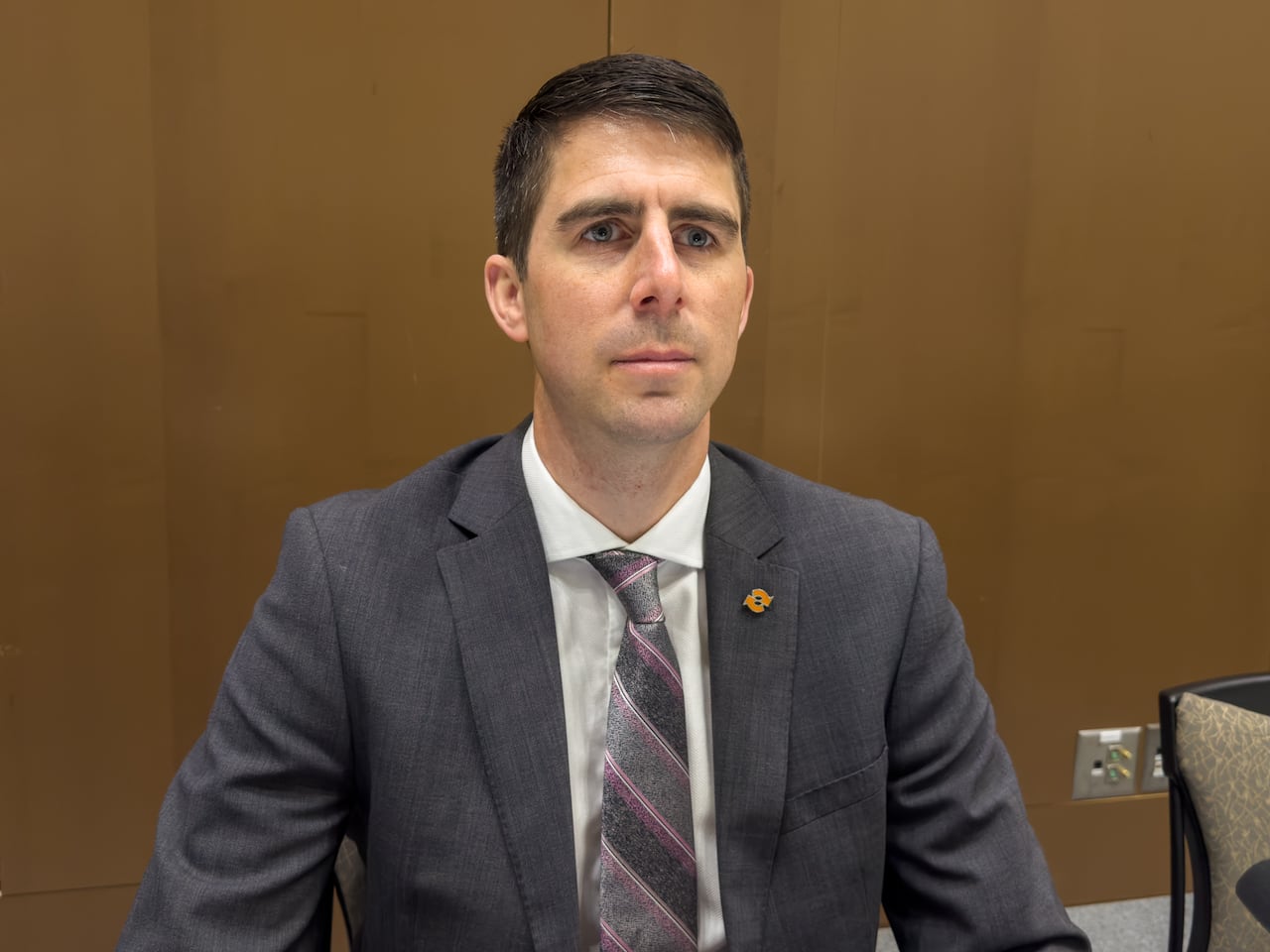 A man in a tie and suit with dark hair.