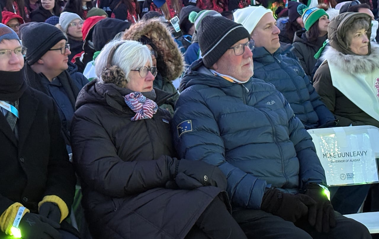 Two people bundled up in winter clothing sit down.