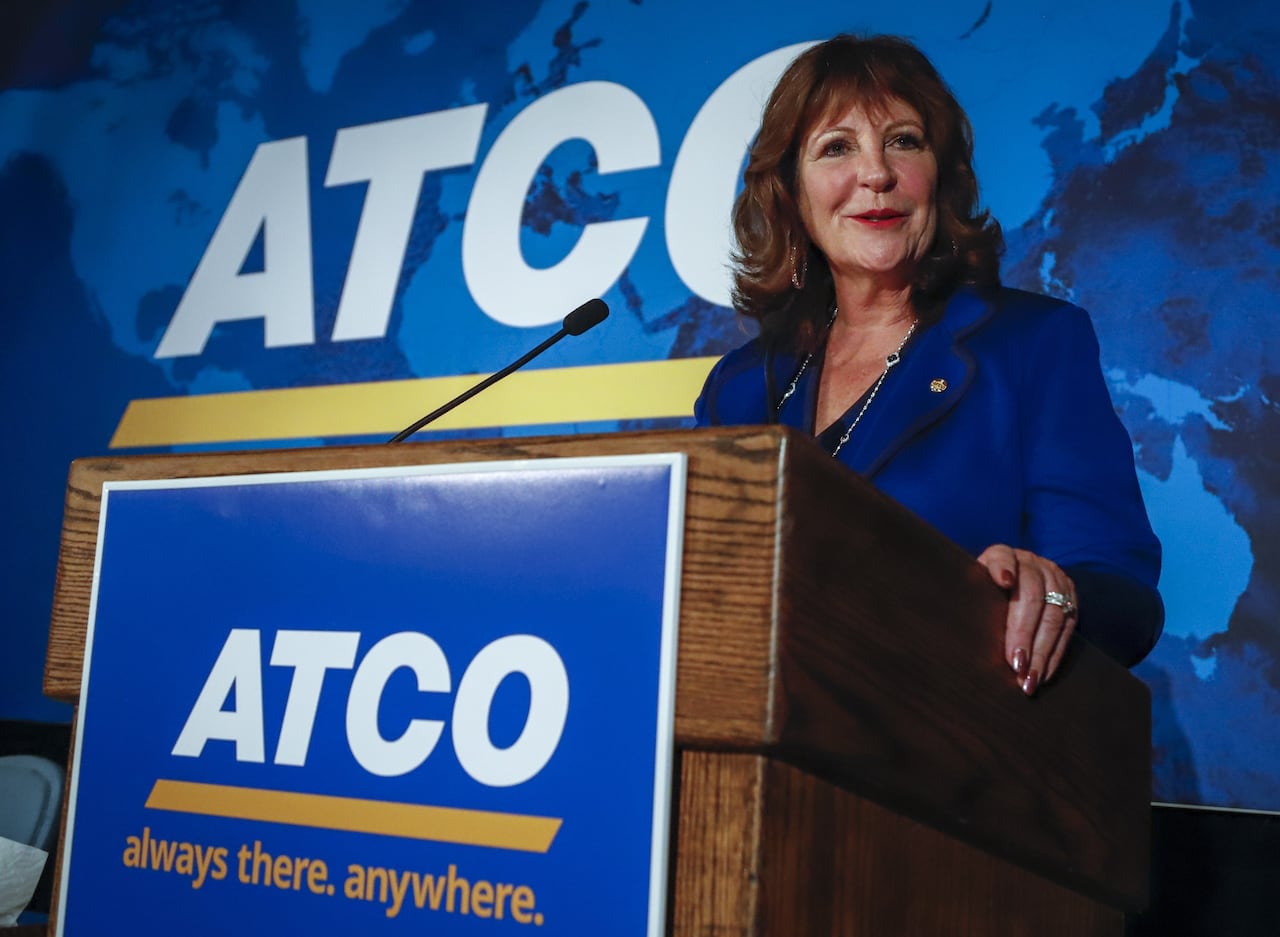 Executive smiles from an ATCO-branded lectern with an ATCO logo behind her.