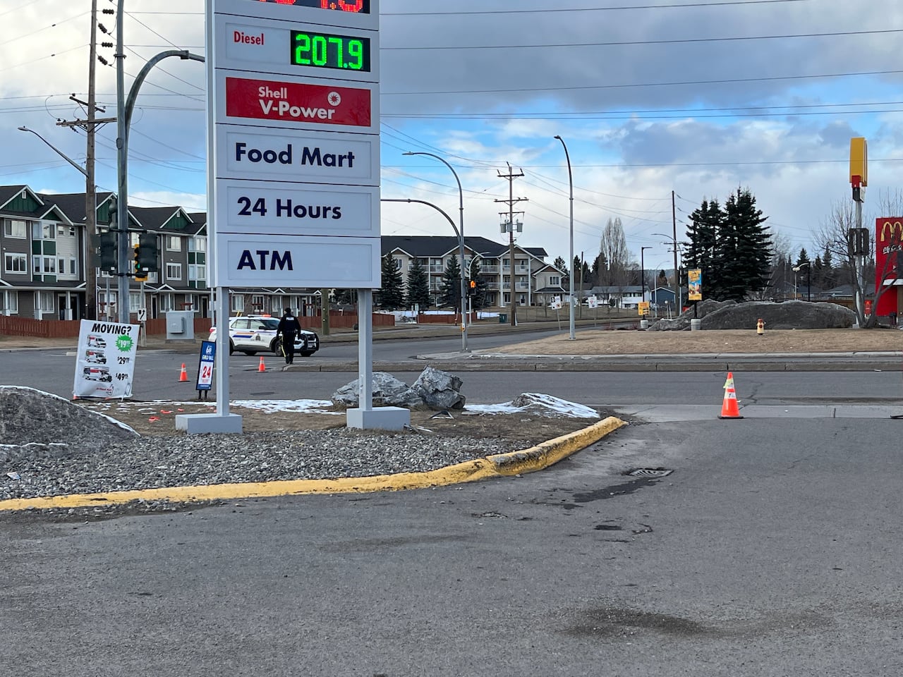 A police vehicle at an intersection beside a gas station sign with a McDonald’s restaurant visible in the background.