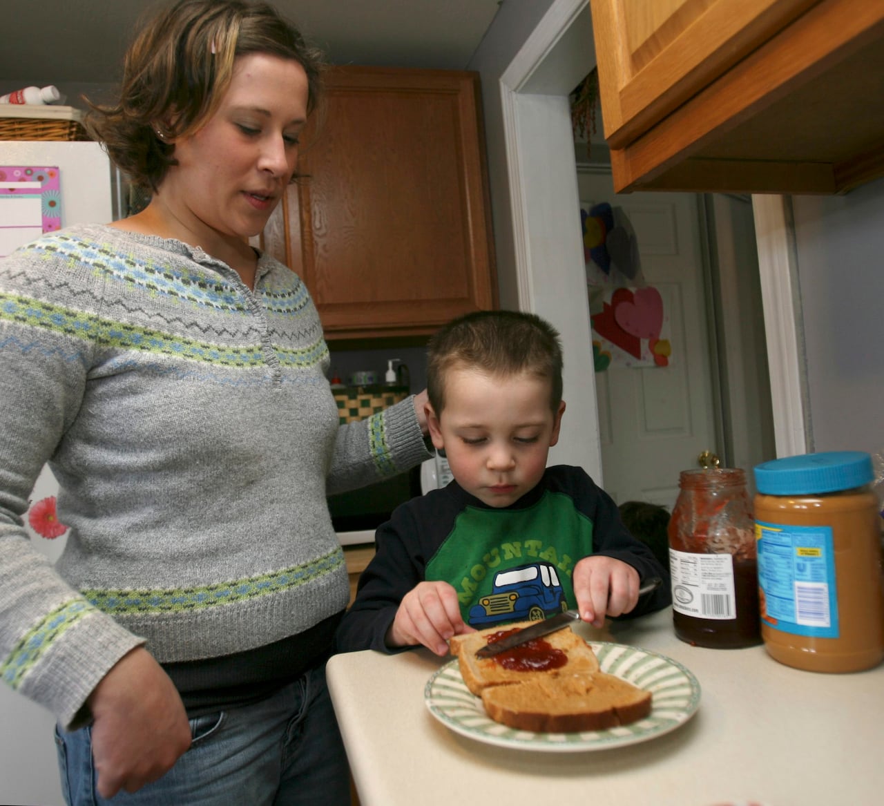 A woman watches her son make his peanut butter and jelly sandwich in this 2009 photo.