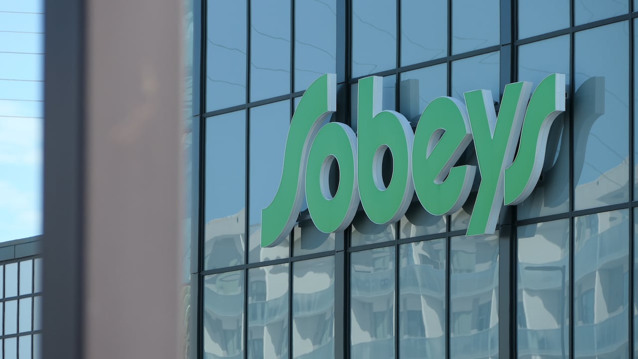 A Sobeys sign on the exterior glass wall of a grocery store.