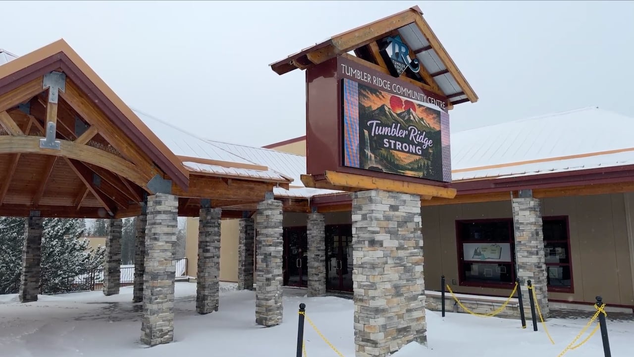 a wood and stone building on a snowy street with a digital sign that says Tumbler Ridge Strong